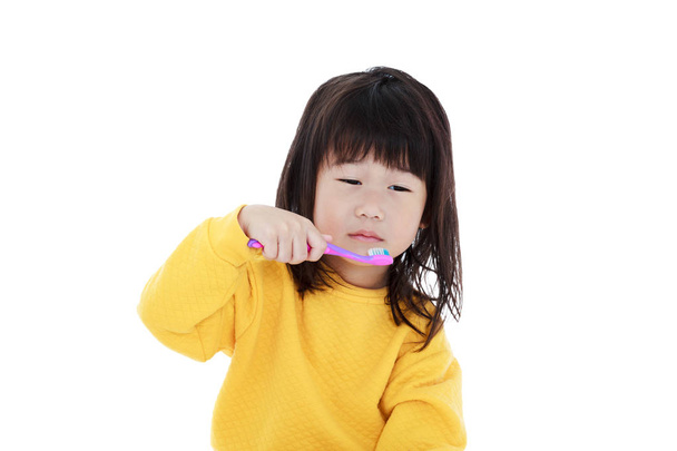 Linda chica asiática con un cepillo de dientes en los dientes de cepillo de mano. Aislado sobre fondo blanco
. - Foto, imagen