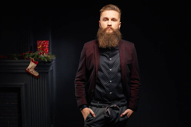 Pěkný stylový muž v tmavě studio s vánoční ponožku na pozadí - Fotografie, Obrázek