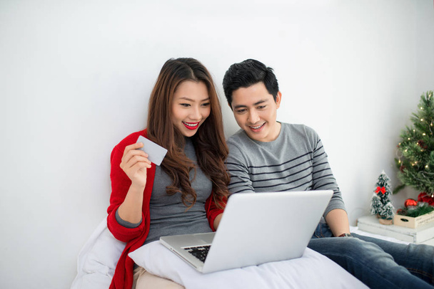 Navidad. asiático pareja compras en línea en casa celebrando año nuevo
. - Foto, imagen