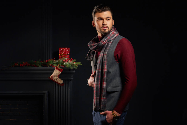 Attractive serious bearded man posing in studio with christmas sock on background - Photo, Image