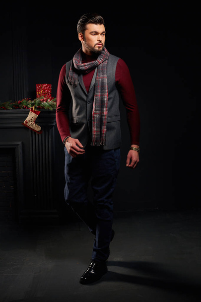 Attractive bearded man posing in dark studio with christmas sock on background - Photo, image