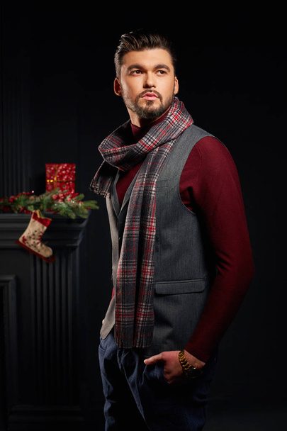 Attractive man standing in studio with christmas sock on background - Valokuva, kuva