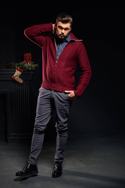 Stylish man in studio with christmas sock on background wearing red jacket - Photo, image