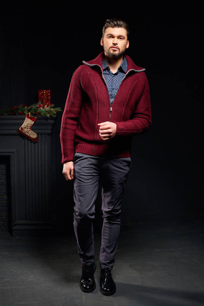 Stylish man in studio with christmas background in red jacket - Photo, image