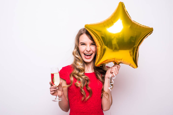 Nuori nainen punainen mekko kulta tähden muotoinen ilmapallo hymyilee ja juo samppanjaa valkoisella taustalla
 - Valokuva, kuva