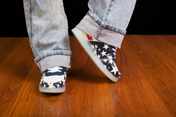 Woman jeans and sneaker shoes on wooden floor - 写真・画像