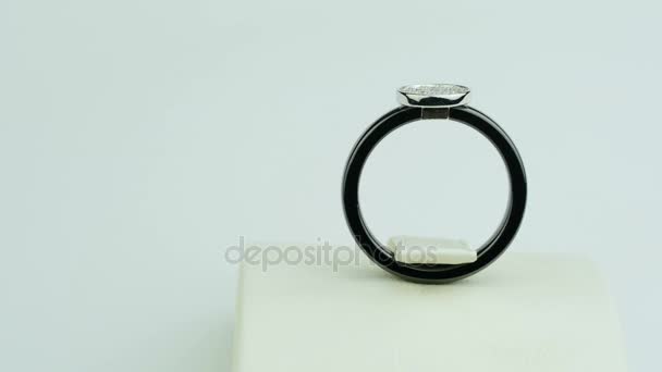 ένα μαύρο δαχτυλίδι είναι με μικρά διαμάντια σε λευκό φόντο - Πλάνα, βίντεο