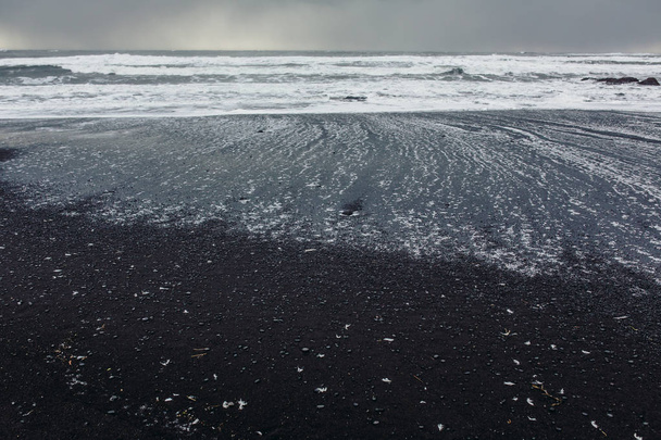Seashore with black sand and stones - Photo, Image