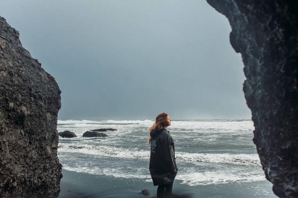 Woman standing on seashore with black sand - Photo, image