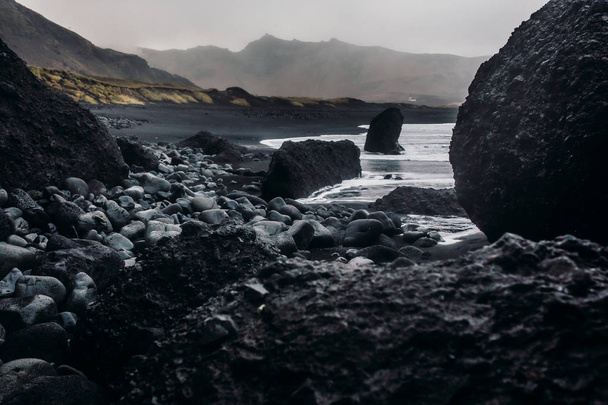 Seashore con sabbia nera e pietre
 - Foto, immagini