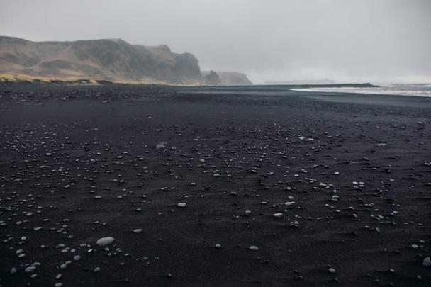 Seashore with black sand and stones - Фото, изображение