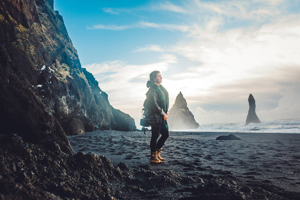 岩の多い海岸に立っている若い女性 - 写真・画像