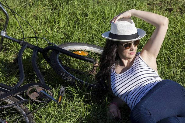 Женщина-туристка с велосипедом лежит на траве
 - Фото, изображение