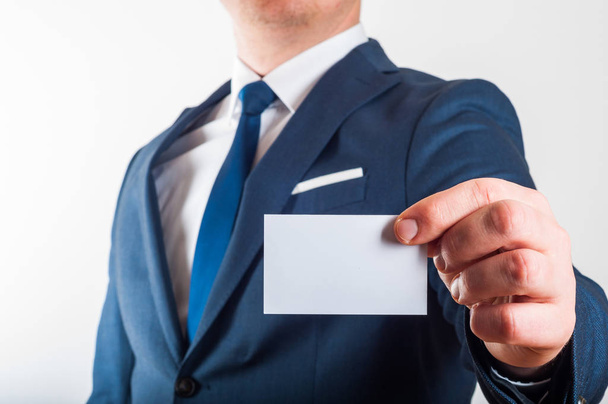 Businessman in suit is showing business card on white background - Photo, Image