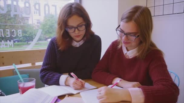 Estudiantes universitarias estudian en la cafetería dos amigas aprendiendo juntas
 - Metraje, vídeo