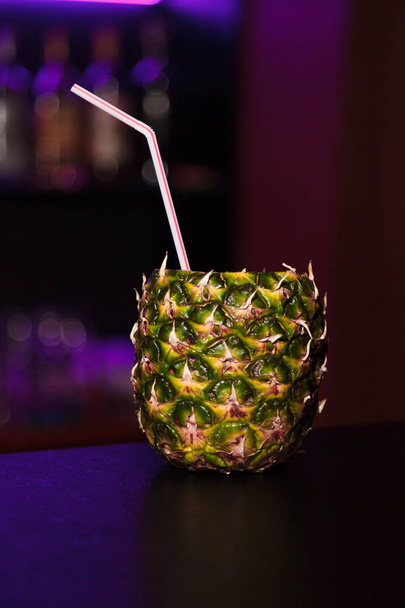 cocktail in een ananas in de bar op een donkere achtergrond van nachtclub - Foto, afbeelding