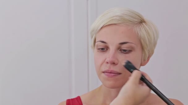 Визажист наносит жидкий тональный фундамент на лицо женщины - Кадры, видео