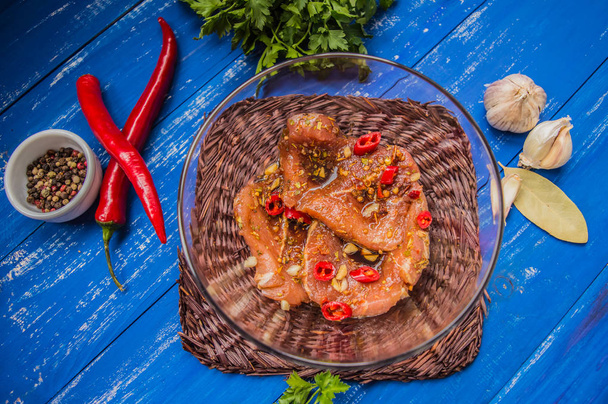 Gemarineerd vlees met specerijen en rode peper. Houten blauwe achtergrond. Bovenaanzicht. Close-up - Foto, afbeelding