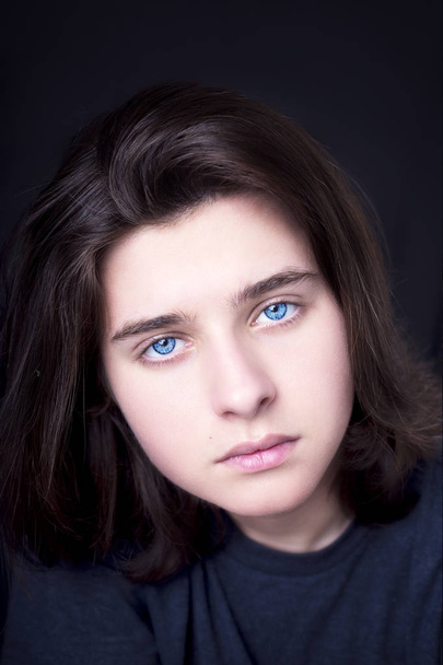 A portrait of a handsome blue eyes teenager on dark background - 写真・画像