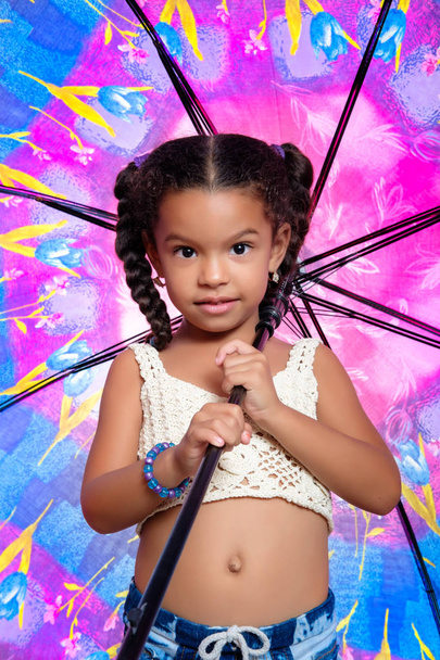 Schattig Afro-Amerikaanse kleine meisje houdt van een kleurrijke paraplu - Foto, afbeelding