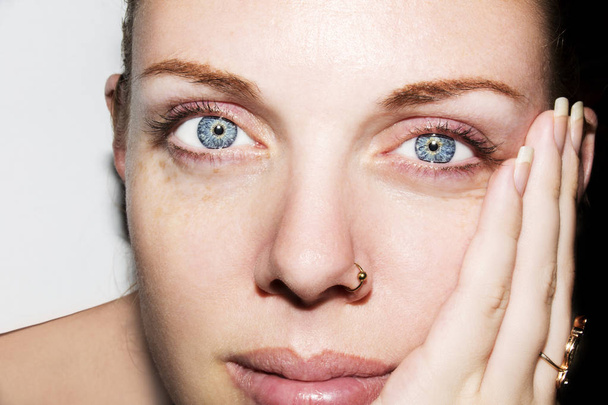 junge Frau mit blauen Augen berührt ihr Gesicht  - Foto, Bild