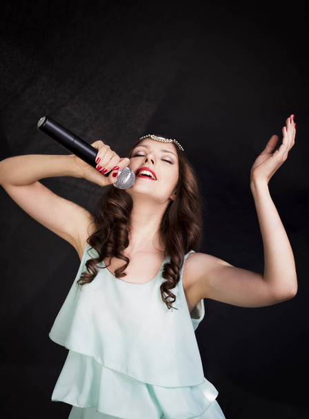 Portrait of beautiful singing woman on black background - Foto, Bild