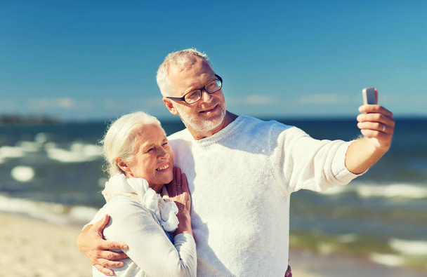 happy senior couple hugging on summer beach - 写真・画像