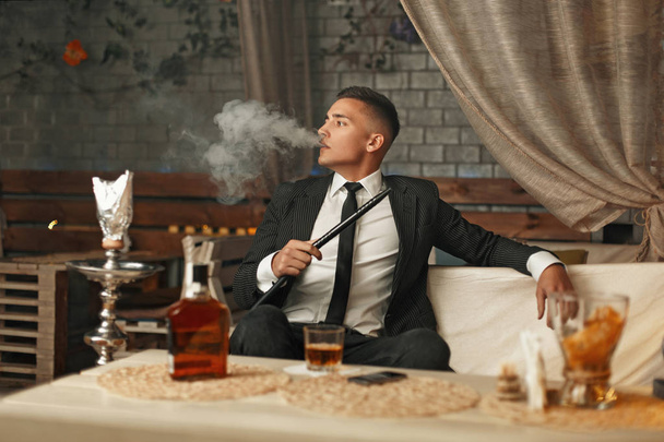 Красивый стильный мужчина в костюме курит кальян
 - Фото, изображение