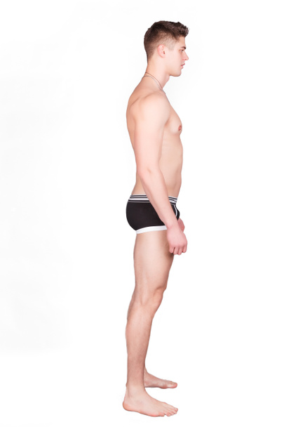 Man in underwear standing on a white background, and turned sideways to the camera - Foto, immagini