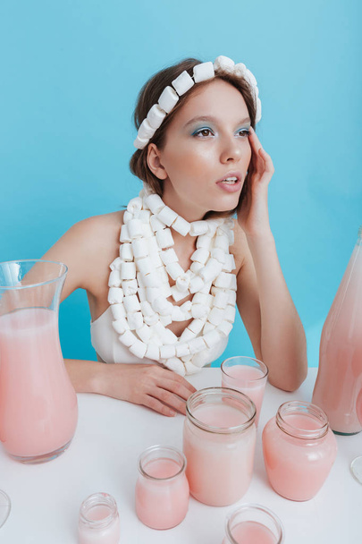 Woman wearing marshmallow necklace at the table with pink juice - Photo, image
