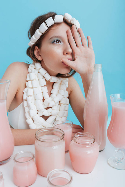 Woman wearing marshmallow necklace at the table with pink beverage - Photo, image