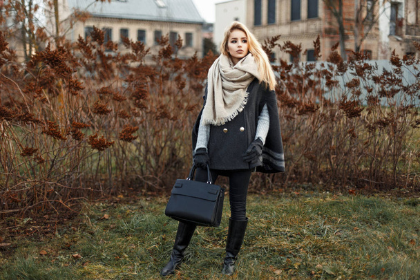 Mooie jonge blonde vrouw in een stijlvolle herfst vacht met een zwarte handtas mode - Foto, afbeelding