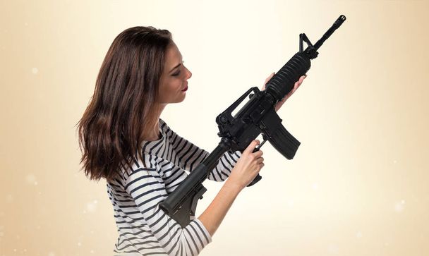 Досить молода дівчина тримає пістолет
 - Фото, зображення
