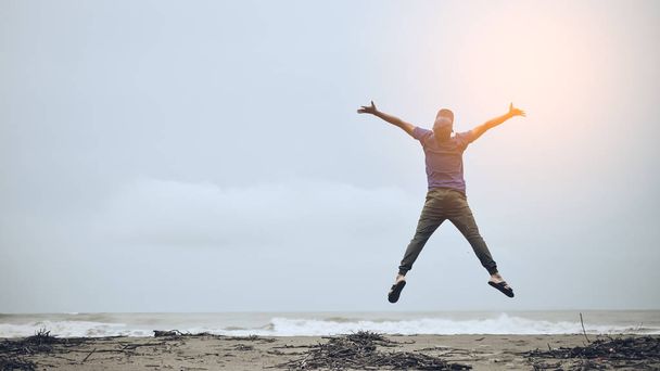 Wohlfühl- und Freiheitskonzept. Kopie eines glücklichen Mannes, der am Strand springt. - Foto, Bild