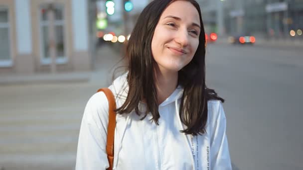 Beautiful teenage woman standing in front of city traffic and smiling - Materiał filmowy, wideo
