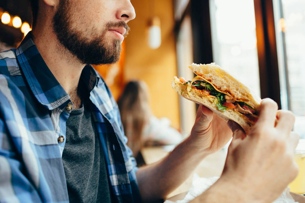 Man in a restaurant eating a hamburger - Fotoğraf, Görsel