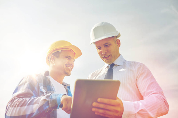 happy builders in hardhats with tablet pc outdoors - Valokuva, kuva