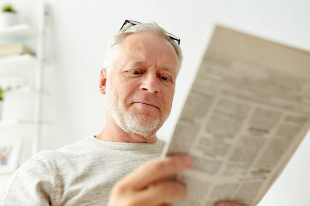 close up of senior man reading newspaper at home - Foto, afbeelding