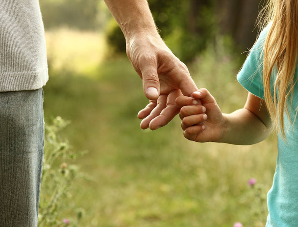 Eltern halten die Hand eines Kindes   - Foto, Bild