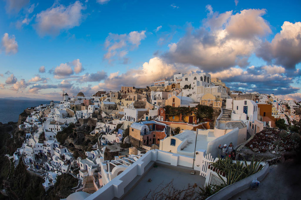 White city on a slope of a hill at sunset, Oia, Santorini, Greec - Foto, Bild