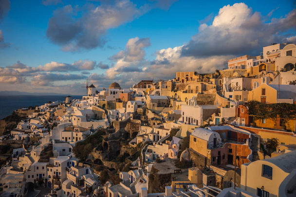 White city on a slope of a hill at sunset, Oia, Santorini, Greec - Фото, изображение