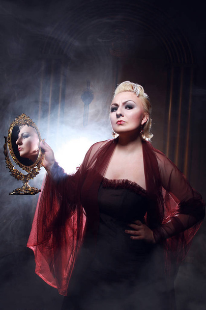 mujer rubia aterradora creando magia con espejo dorado
 - Foto, Imagen