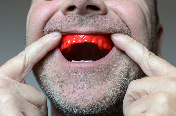 Muž umístění kousnutí desku v jeho mouthred  - Fotografie, Obrázek