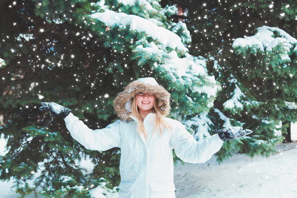 Mladá veselá žena v kápi s fun fur na ulici. V zimě studené slunečný den na pozadí stromů a sněhu.  - Fotografie, Obrázek