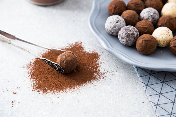 Trufas de chocolate sortidas com cacau em pó, coco e avelãs picadas em um prato de sobremesa
 - Foto, Imagem