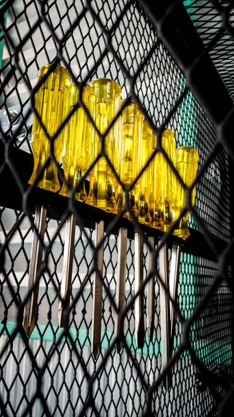 Κίτρινο κατσαβίδι σε ένα κλουβί αποθήκευσης. - Φωτογραφία, εικόνα