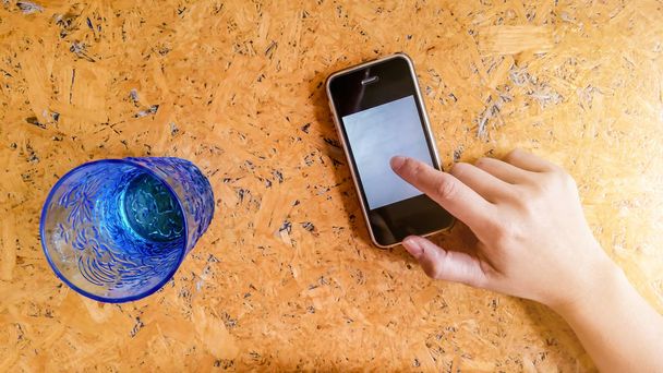 Hands are using smartphones and Blue Glass with water. - Foto, Bild