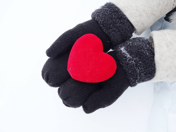 Руки женщины в рукавицах с красным сердцем на снегу
 - Фото, изображение