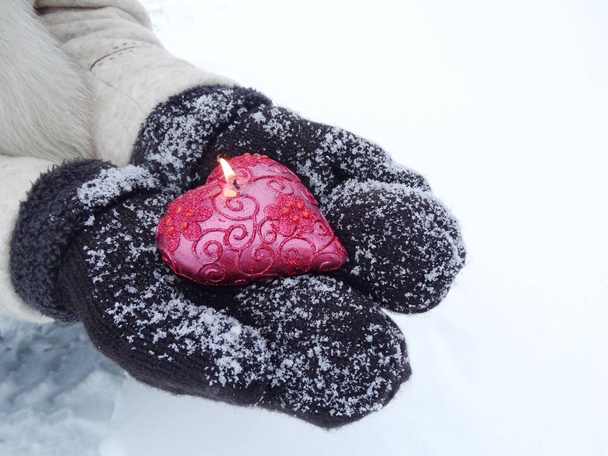 Frauenhände in Fäustlingen mit rotem Herz auf Schnee - Foto, Bild