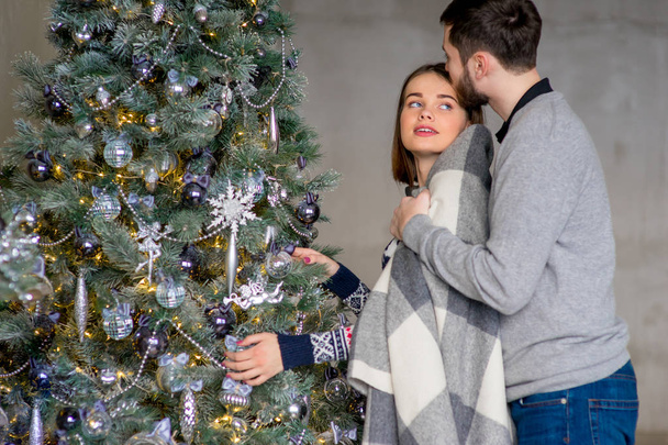 Happy couple of lovers decorating Christmas tree - Foto, afbeelding